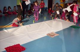 Bambini che incollano il loro disegno su una grande bandiera italiana