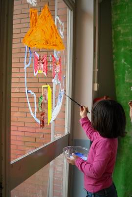 Bambina che dipinge il mondo sulla vetrata della scuola